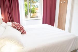 a bedroom with a white bed with red curtains and a window at Casa Marino in Sorrento