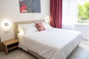 a white bed with a red pillow on it in a bedroom at Casa Marino in Sorrento