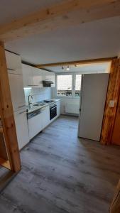 eine große Küche mit weißen Geräten und Holzböden in der Unterkunft Berner Oberland Am Thunersee in Därligen