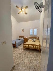 een slaapkamer met 2 bedden en een plafondventilator bij A cheerful chalet villa few steps to the beachside in Marsa Matruh