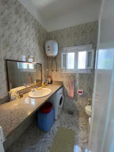 een badkamer met een wastafel, een toilet en een spiegel bij A cheerful chalet villa few steps to the beachside in Marsa Matruh