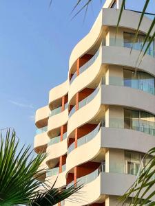 a tall building with palm trees in front of it at Amare Hotel in Shëngjin