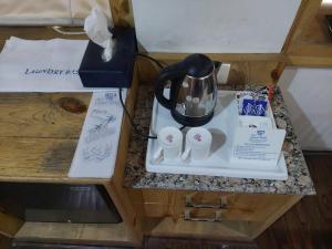 a counter top with a coffee pot and cups on it at Hotel Grand Habib in Srinagar