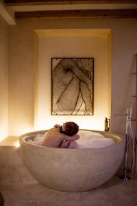 a woman laying in a bath tub in a bathroom at Pollicastro Boutique Hotel in Lecce