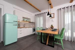 a kitchen with a wooden table and green chairs at Modern Dome Homes Of Santorini in Perissa