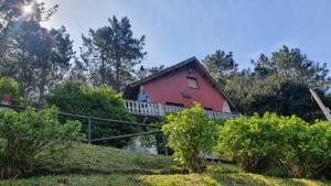 a red house on top of a hill with trees at Villa Alejandra in Cudillero