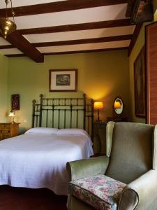 um quarto com uma cama grande e uma cadeira em Posada de San Millán em Sepúlveda