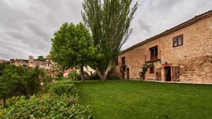 a yard with a tree and a brick building at Posada de San Millán in Sepúlveda