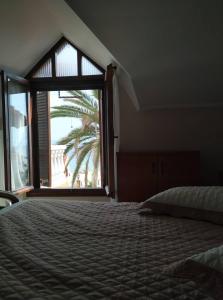 sypialnia z łóżkiem i dużym oknem w obiekcie Palm Garden Villa w mieście Orfánion