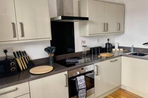 eine Küche mit weißen Schränken und einem schwarzen Gerät in der Unterkunft Luxury, centrally located 2 bed modern apartment in Great Yarmouth