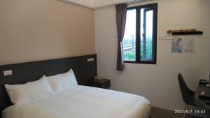 a bedroom with a white bed and a window at 沐谷親子溫泉會館 in Jiaoxi