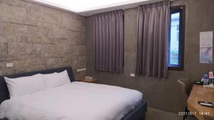 1 dormitorio con cama blanca, escritorio y ventana en 沐谷親子溫泉會館 en Jiaoxi