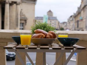 a table with a bowl of pastries and orange juice at Studio rénové avec terrasse et vue unique ! in Caen