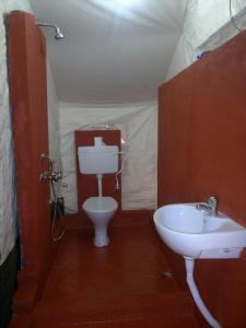 a bathroom with a sink and a toilet in a tent at Nature Camp Konark Retreat in Konārka