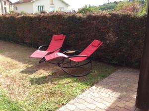 deux chaises rouges assises à côté d'une haie dans l'établissement Le Cottage des Mésanges, à Villefranche-de-Rouergue
