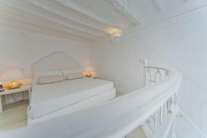 a white bedroom with a bed and a desk at La Settima Luna Hotel in Canneto