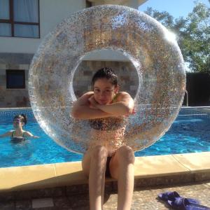Una ragazza è seduta in una grande palla di metallo vicino a una piscina di Byala Vista Beach Apartments D - Бяла Виста Бийч Апартментс Д a Byala