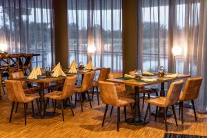 ein Esszimmer mit Tischen, Stühlen und Fenstern in der Unterkunft Das ELB Boardinghouse Hotel Restaurant in Magdeburg