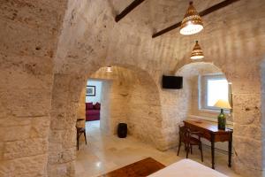 a room with a stone wall with a table and a window at Terrazze Sulla Valle in Martina Franca