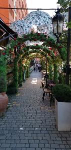 una pasarela con un arco con flores y un banco en Apartment Royal, en Pristina