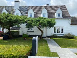 una casa con un albero di fronte di Begijnhof 13 Holiday Home a Zuienkerke