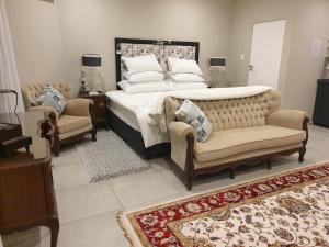 a bedroom with a bed and a couch and chairs at House Mulberry Guesthouse in Pretoria