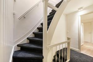 een trap in een huis met witte muren en zwart tapijt bij Adam's Suite in Amsterdam