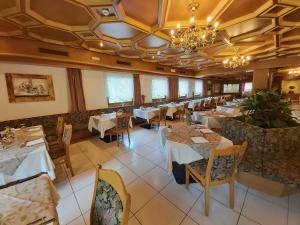 a restaurant with tables and chairs and a chandelier at Albergo Scoiattolo in Falcade