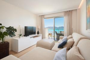 a white living room with a couch and a tv at SA MANIGA 6-H in Cala Millor