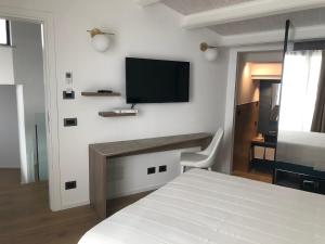 1 dormitorio con 1 cama y TV en la pared en PALAZZO RAHO SUITES, en Cefalú