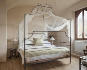 sypialnia z łóżkiem z baldachimem i białą pościelą w obiekcie Castello di Gabiano w mieście Gabiano