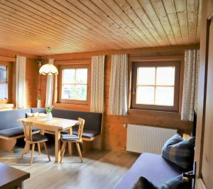 a living room with a table and chairs and two windows at Ferienwohnung Gassenhof in Matrei in Osttirol