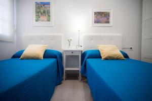 1 dormitorio con 2 camas azules y mesa en El Embrujo de La Caleta Ha Apartment en Cádiz