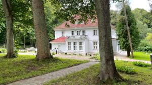 una casa blanca en medio de árboles en Villa ANSER en Połczyn-Zdrój