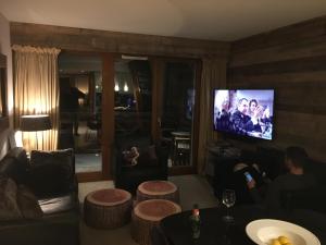 a living room with a couch and a tv at Les Ecureuils Squirrel Lodge in Oz