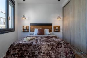 a bedroom with a large bed and two lights at Apartamentos luxury Doña Bella 2a in Ayamonte