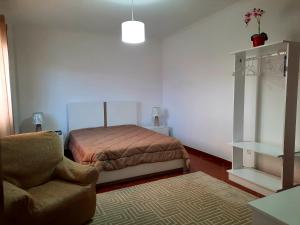 um quarto com uma cama e uma cadeira em Arrivillage em Arrifes