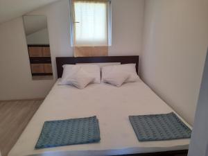a small bedroom with a bed with two pillows at Apartmani Goga in Pirovac