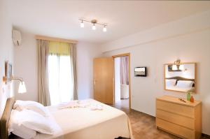 a bedroom with a bed and a dresser and a television at Miraluna Aparthotel in Lefkos Karpathou