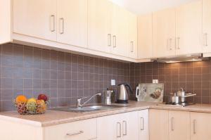 a kitchen with white cabinets and a bowl of fruit on the counter at Miraluna Aparthotel in Lefkos Karpathou