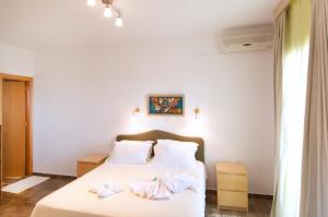a bedroom with a white bed with two towels on it at Miraluna Aparthotel in Lefkos Karpathou
