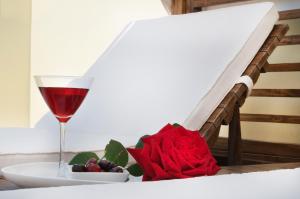 a glass of wine and a bowl of fruit and a rose at Miraluna Aparthotel in Lefkos Karpathou