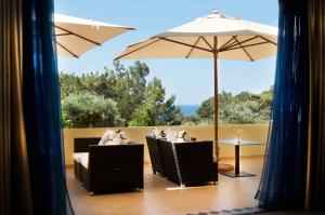 a patio with two chairs and an umbrella at Miraluna Aparthotel in Lefkos Karpathou