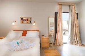 a bedroom with a bed with white sheets and a window at Miraluna Aparthotel in Lefkos Karpathou