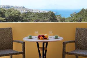 a table with a bowl of fruit and two chairs at Miraluna Aparthotel in Lefkos Karpathou