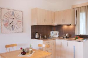 a kitchen with a clock on the wall and a table at Miraluna Aparthotel in Lefkos Karpathou