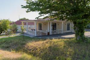 a white house with a porch and a tree at Gabala Shooting Club in Gabala