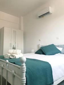 Blue Seaview Appartments في بافوس: غرفة نوم بسرير ابيض مع بطانيه خضراء