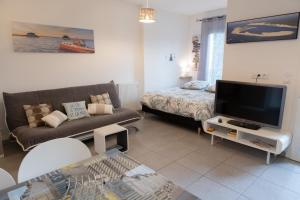 a living room with a couch and a tv at Appartement T1bis centre ville Andernos Les Bains in Andernos-les-Bains