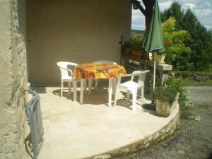 um pátio com uma mesa e cadeiras e um guarda-sol verde em Maison de campagne MONTCUQ en Quercy Blanc em Montcuq